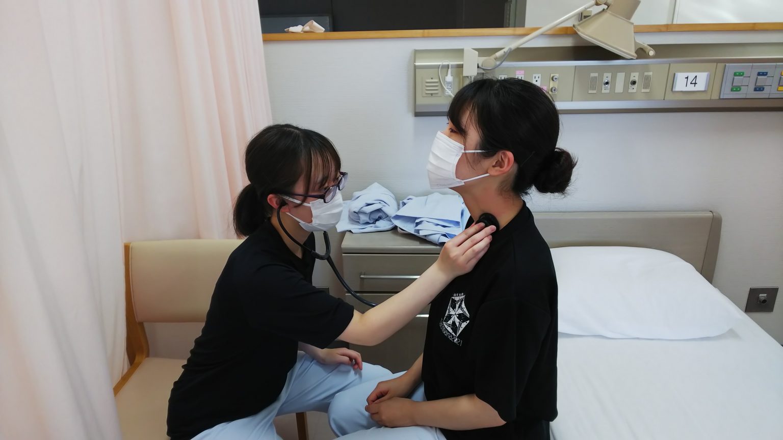 看護技術の実習中、学生が患者の聴診を行っている様子。