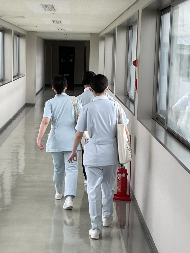 医大付属病院の実習病棟に向かう4年生の学生たちが廊下を歩いている様子。