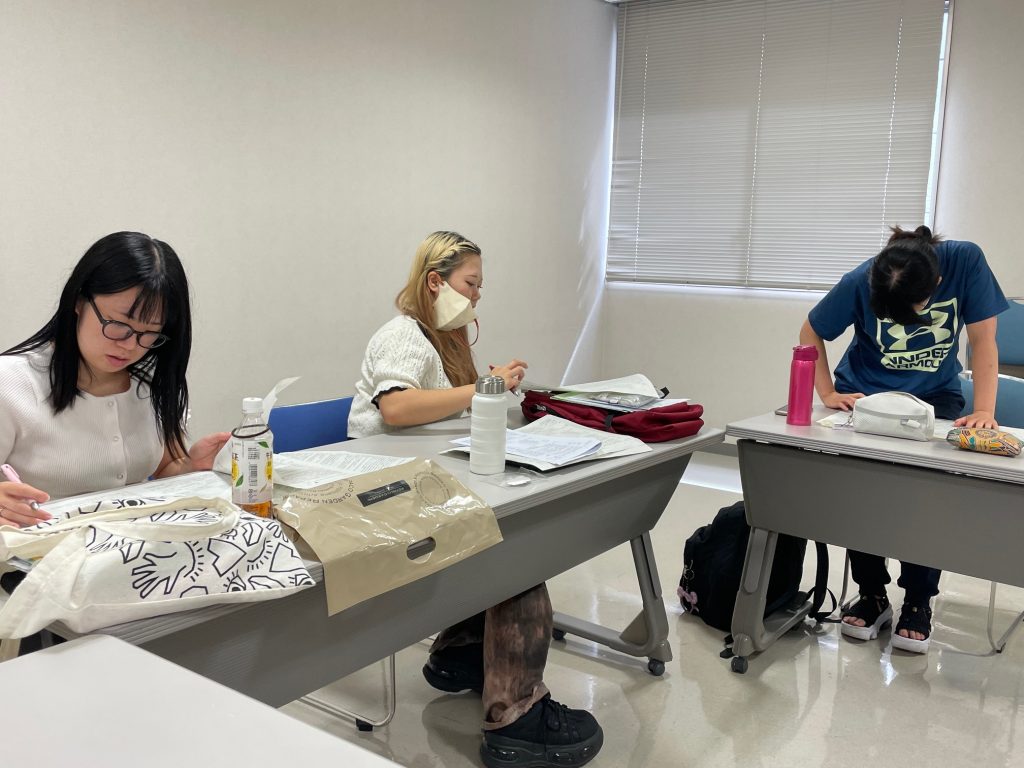 明日の統合実習報告会に向けて練習中の学生たちが、机に向かって作業している様子。