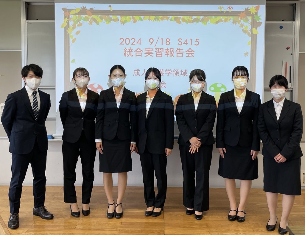 2024年度統合実習報告会に参加した学生たちが、マスクを着用して整列している様子。背景には報告会のタイトルが表示されている。