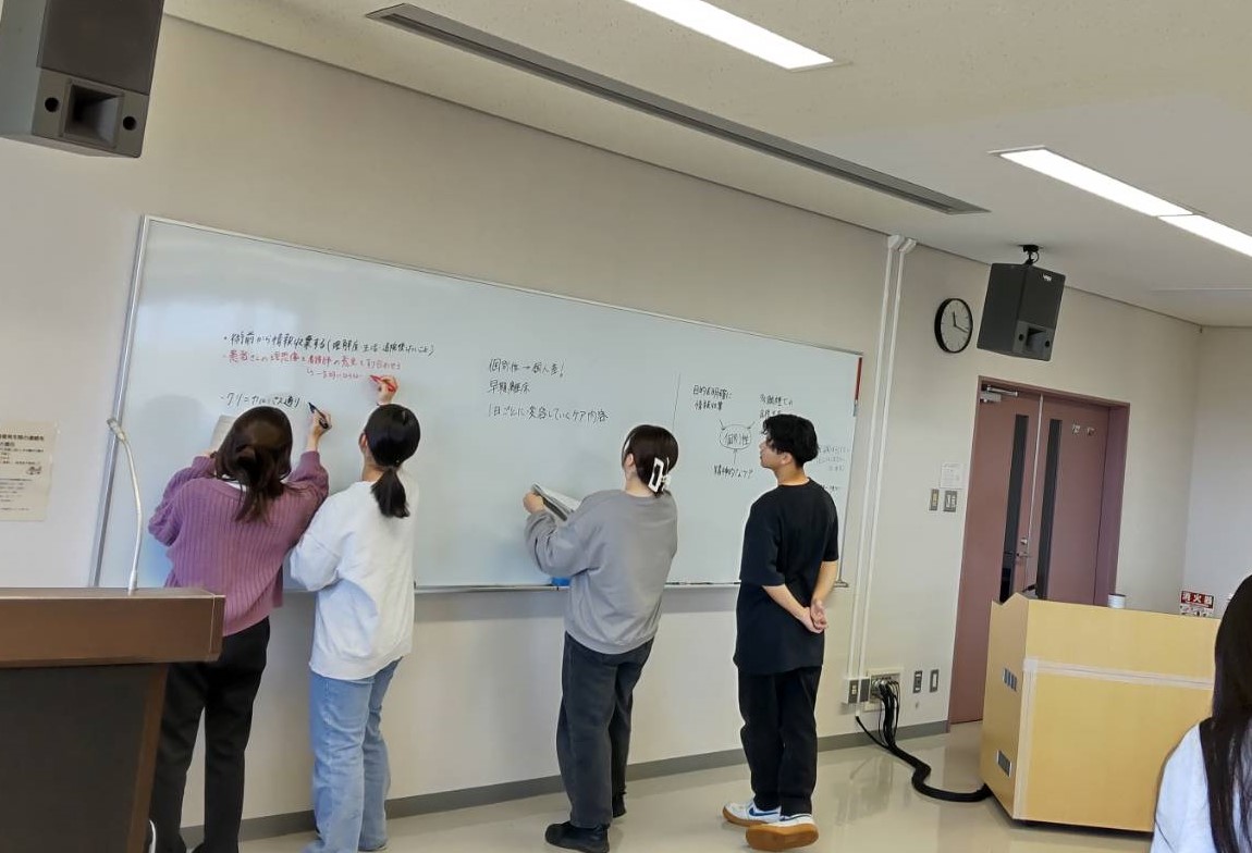 領域別実習の合同カンファレンスで、学生たちがホワイトボードに意見を共有している様子。
