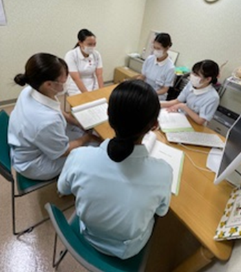 実習指導者からアドバイスを受ける看護学生たちがカンファレンスを行っている様子。