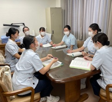 看護学生たちがテーブルを囲んで実習について話し合っている様子。