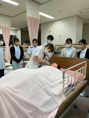 看護技術の演習で、学生たちが洗髪のデモンストレーションを見学している様子。