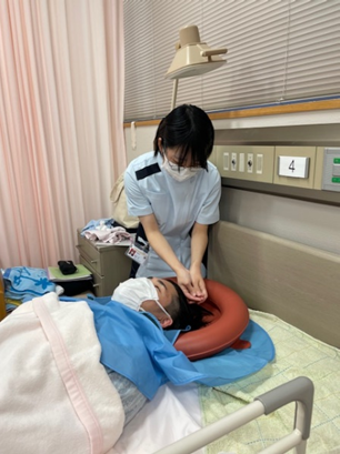 看護学生が患者の洗髪を行っている演習の様子。患者はリラックスした表情で、看護技術を学ぶ学生が真剣に取り組んでいる。