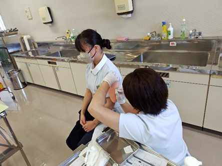 看護技術の演習で筋肉内注射を受ける学生と指導者の様子。