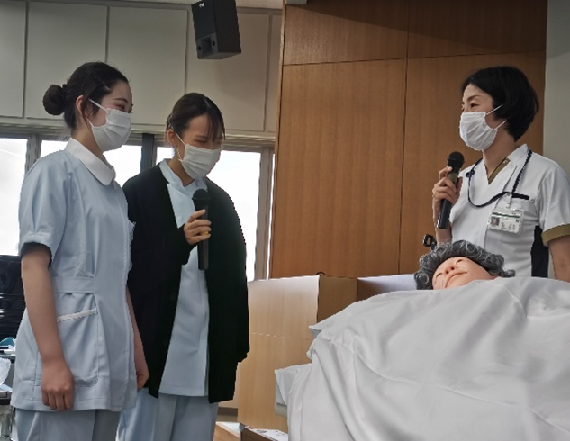 看護技術の演習で、体温に関するグループ活動を行う学生たちが、模擬患者に対する援助を考えている様子。