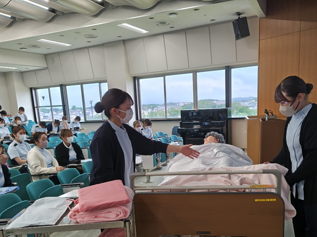 看護技術の演習で、学生が体温管理のために患者にケアを行っている様子。