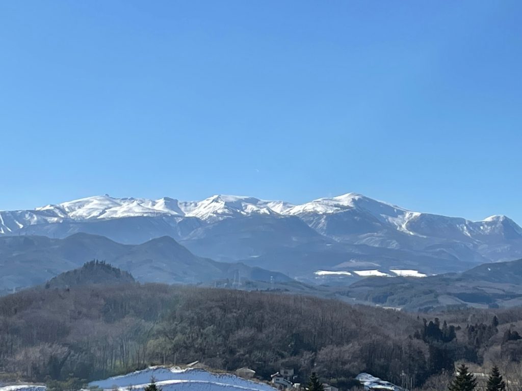 看護学部から見える雪をかぶった山々の美しい稜線と青空の風景。