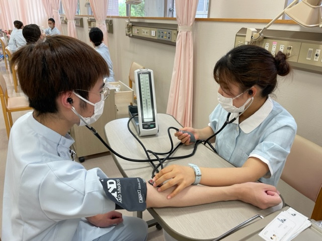 看護学部の学生が血圧測定を行い、手技を確認している様子。