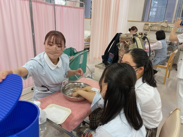 看護学部のオープンキャンパスで、高校生に手浴の体験を提供している様子。