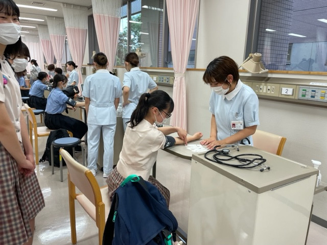看護学部のオープンキャンパスで血圧測定を行う学生たちの様子。