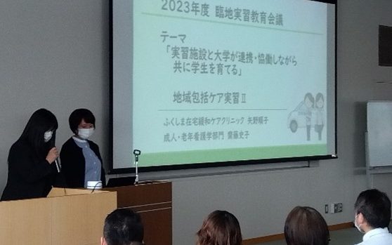 2023年度臨地実習教育会議で発表を行う講演者とスクリーンの内容が映る会場の様子。