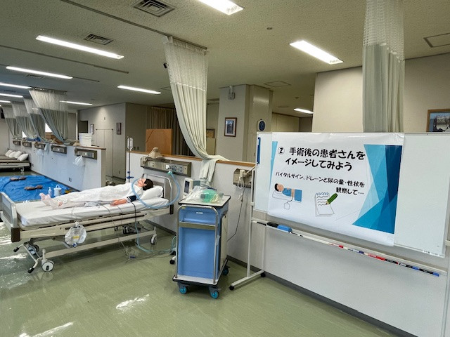 手術後の患者がベッドに横たわり、医療機器が周囲に配置された病室の様子。