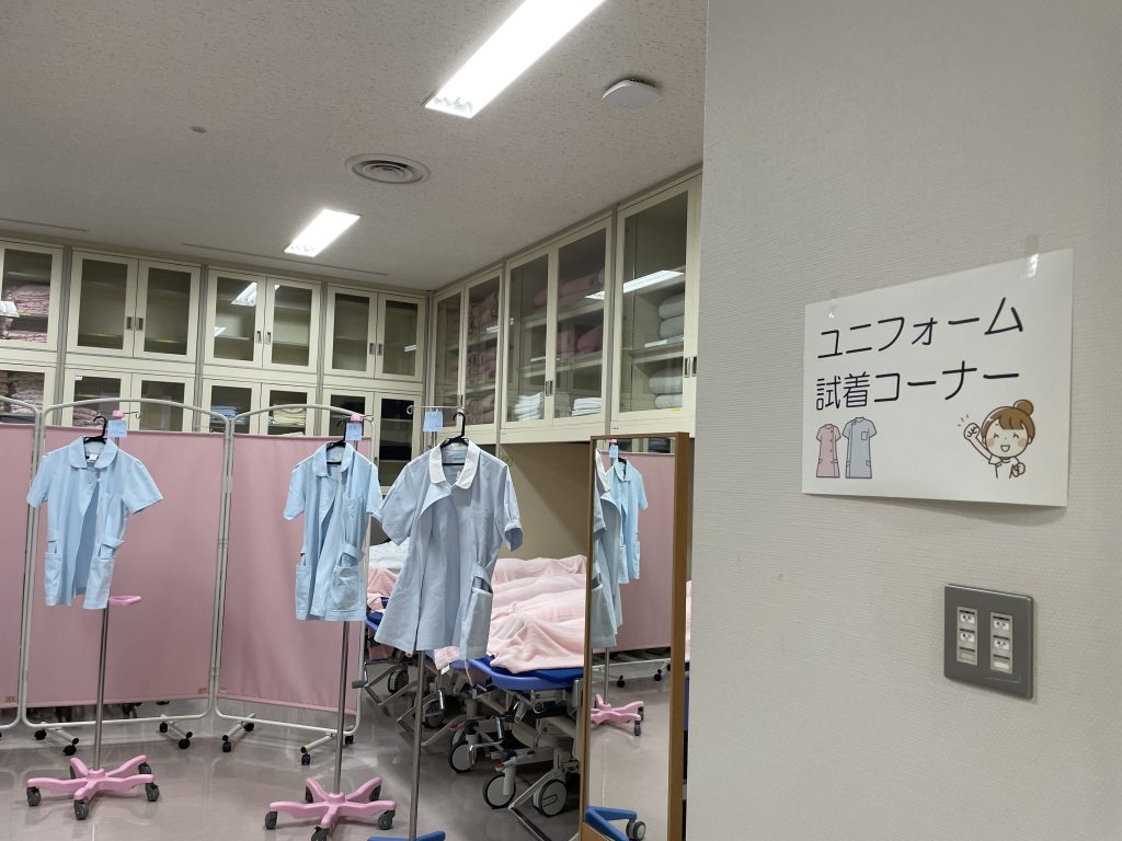 看護学部の実習着試着コーナーには、水色の実習着が並んでいます。