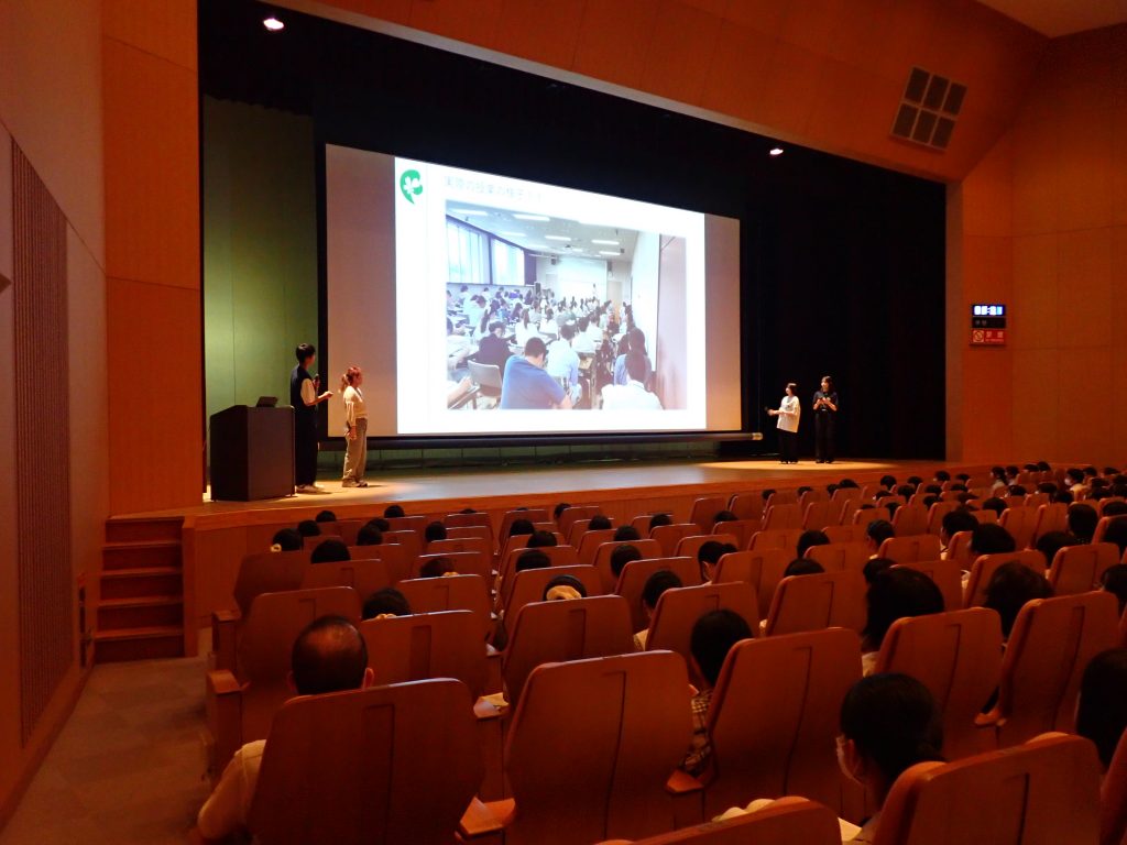令和6年看護学部オープンキャンパスの講堂での模擬講義の様子。多くの学生が参加している。