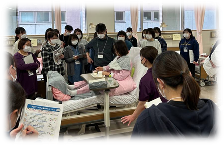 福島県立医科大学でのデモンストレーション中の医療研修の様子。参加者が患者に対して学びながら観察している。