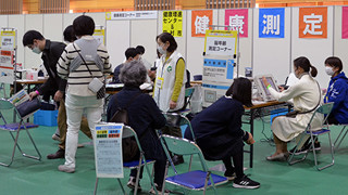 Health promotion event at a center, with people engaging in health screenings and consultations.