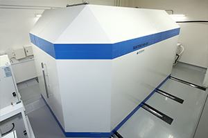 小型サイクロトロンHM-20の外観、白と青のデザインが特徴的な研究機器。