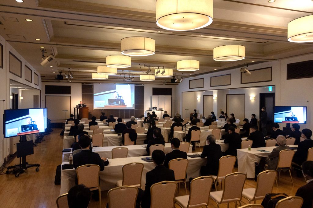 放射性治療薬開発に関する国際シンポジウムの会場の様子、参加者が講演を聴いている。
