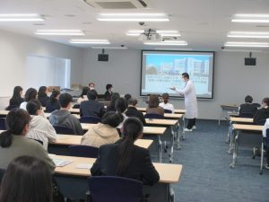 ふくしま国際医療科学センターでの中高生見学会の様子。講師がプレゼンテーションを行い、参加者が聴講している。