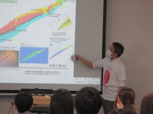 ふくしま国際医療科学センターでの中高生見学会の様子。講師が資料を指し示しながら説明している。
