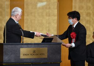 河北文化賞を受賞するために、壇上で表彰状を受け取る男性と授与者の様子。