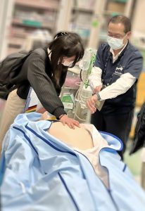医療現場での見学会の様子。学生が医療スタッフと共に患者のケアを学んでいる。