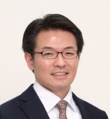 講座主任の田巻倫明教授のポートレート写真。ビジネススーツを着用し、笑顔でカメラを見つめている。