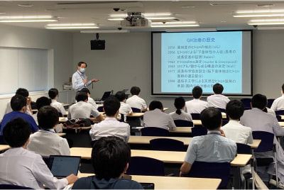 甲状腺・内分泌グランドカンファレンスで講演する医師と参加者たちの様子。