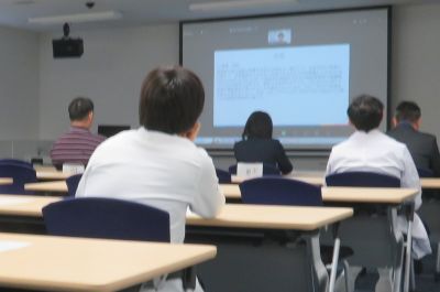FMU成果報告会で講演を聴く参加者たちが、スクリーンに映る資料を見つめている様子。