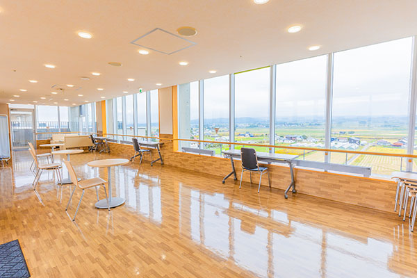 テーブルと椅子が配されたフロア。大きな窓からは緑豊かな風景が広がる。