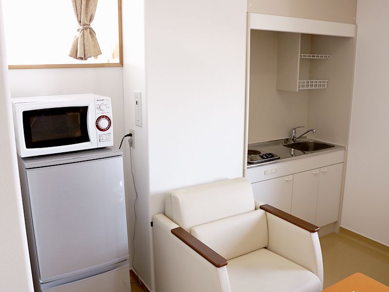 室内に備えた電子レンジ、冷蔵庫、ミニキッチンの写真。