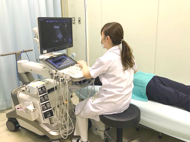 診療台と医療機器が並び、医療スタッフがパソコン画面を確認している。