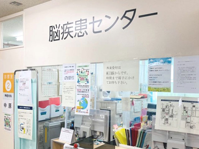脳疾患センターの受付エリア。壁には診療案内やポスターが掲示され、内部には書類や設備が整然と配置されている。
