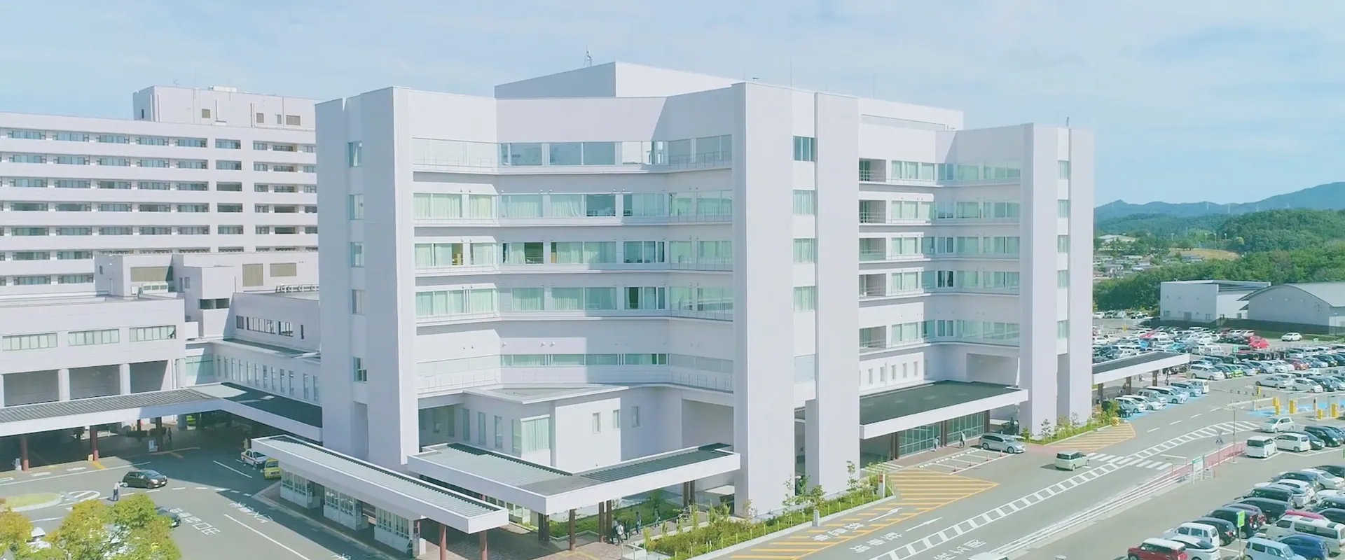 福島県立医科大学附属病院の外観、白い建物と広い駐車場が見える。