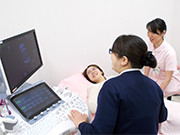 医療スタッフが患者の超音波検査を行っている様子。白衣のスタッフがモニターを見ながら操作しています。