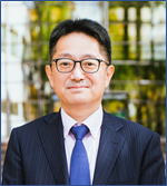 部長の藤井正純教授がスーツを着て微笑んでいるポートレート。背景には緑の植物が見える。