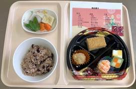 栄養管理部の食事プレート、黒米ご飯と彩り豊かな副菜、デザートが盛り付けられたトレイ。