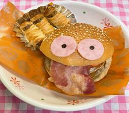 ユニークな顔を持つハンバーガーと、焼き菓子が盛り付けられた皿の画像。