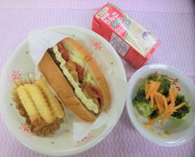 栄養管理部の食事プレートには、ホットドッグ、フライドポテト、サラダ、牛乳が盛り付けられています。