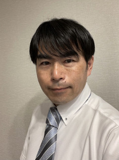 部長の林哲生がスーツを着て微笑んでいるポートレート。リハビリテーションセンターのスタッフ紹介用。