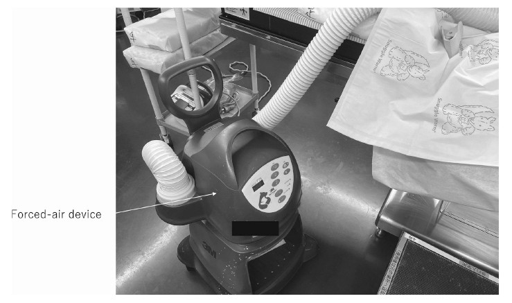 Forced-air device used in medical settings, featuring a control panel and flexible tubing.