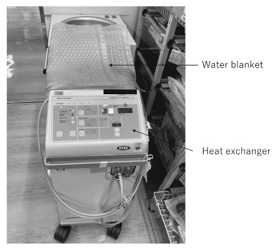 Forced-air warming device with a water blanket and heat exchanger, used for temperature management in neurosurgery.