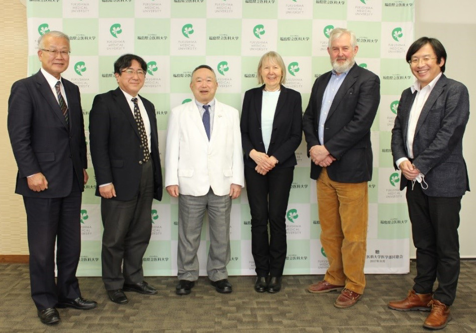 6人の男女が福島医科大学のロゴが入った背景の前で並んで立っている。フォーマルな服装で笑顔。