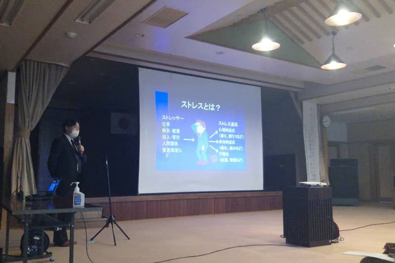 ストレスについて説明する講師が、パワーポイントを使って講演を行っている様子。