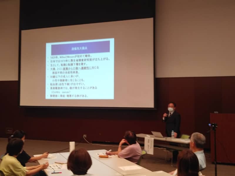 潰瘍性大腸炎・クローン病に関する講演会の様子。講師がスライドを使って説明している。
