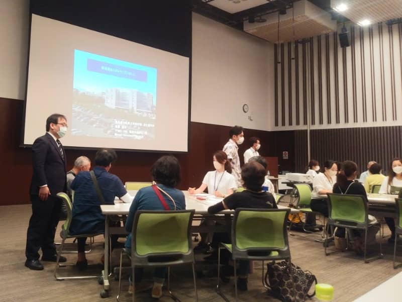 医療講演会での参加者と講師が交流している様子、背景にはプレゼンテーションが映し出されている。