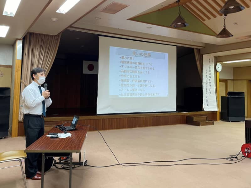 講演会で話す大平哲也教授とスクリーンに映し出されたスライドの様子。