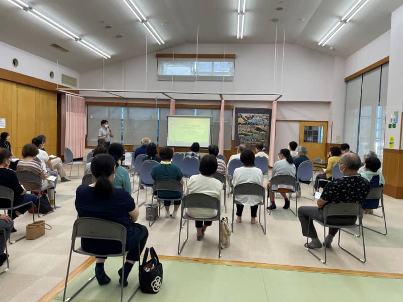 健康長寿をテーマにした講演会の様子。参加者が椅子に座り、講師の説明を聞いている。